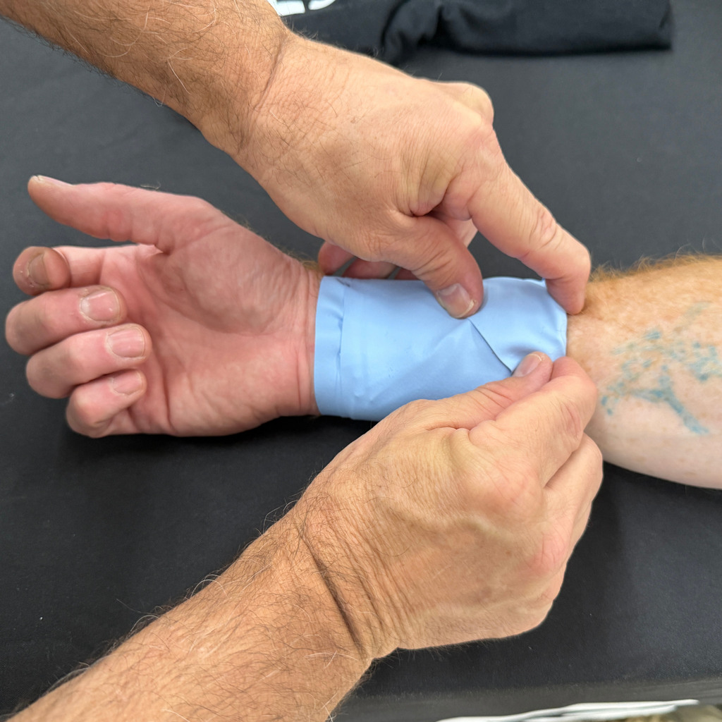 Person applying an ESMARK bandage to another person's wrist
