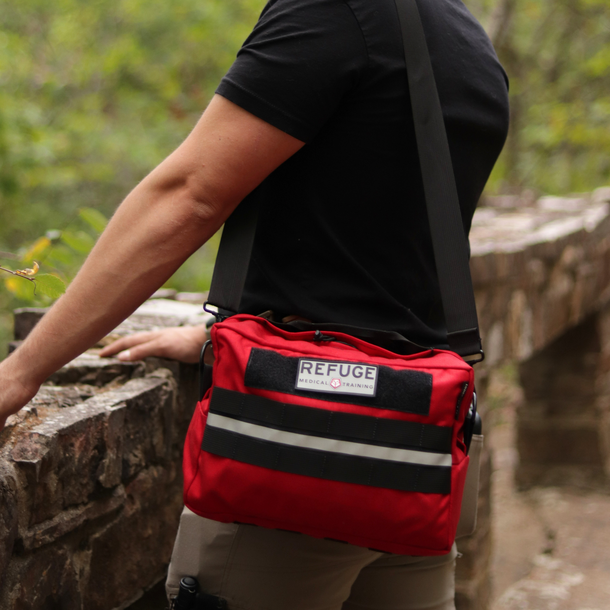 Person wearing a red Refuge Medical Adventure Bag with shoulder strap