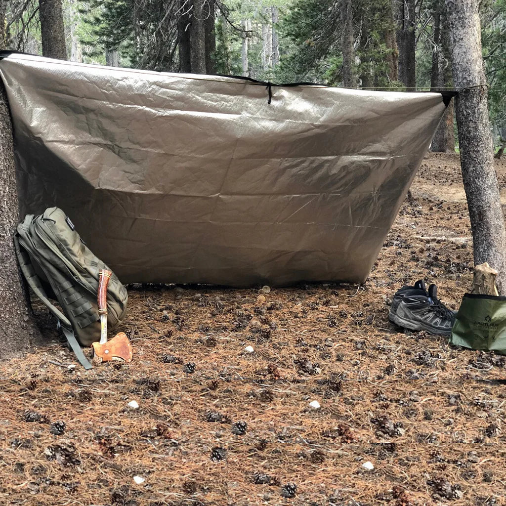 Arcturus Survival Blanket tied up to trees being used as a shelter for camping