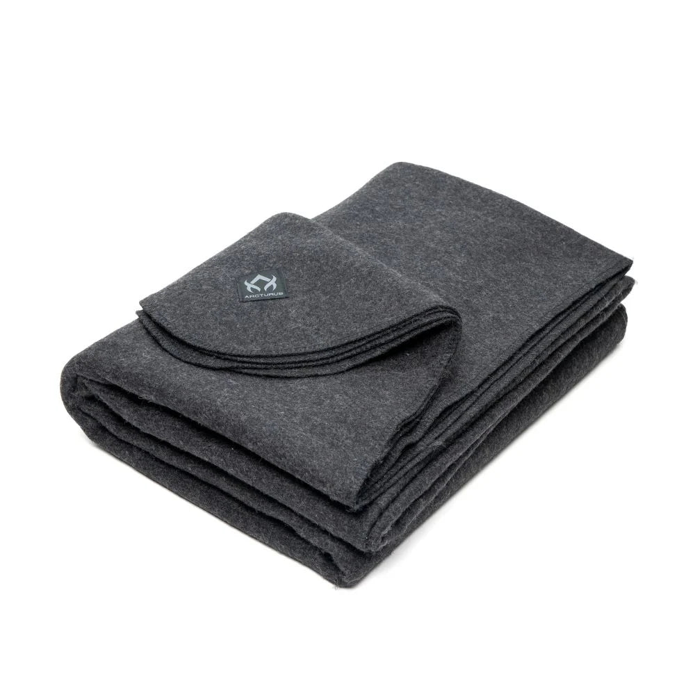 A folded dark gray wool Arcturus blanket with a visible brand logo on the lower right corner.