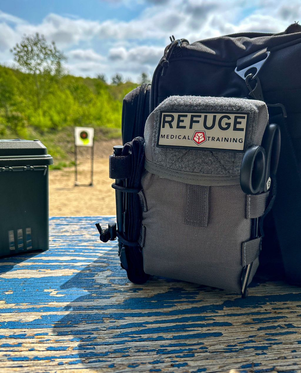 Refuge Medical BearMIN First Aid Kit - Gray Staged on a table at a shooting range