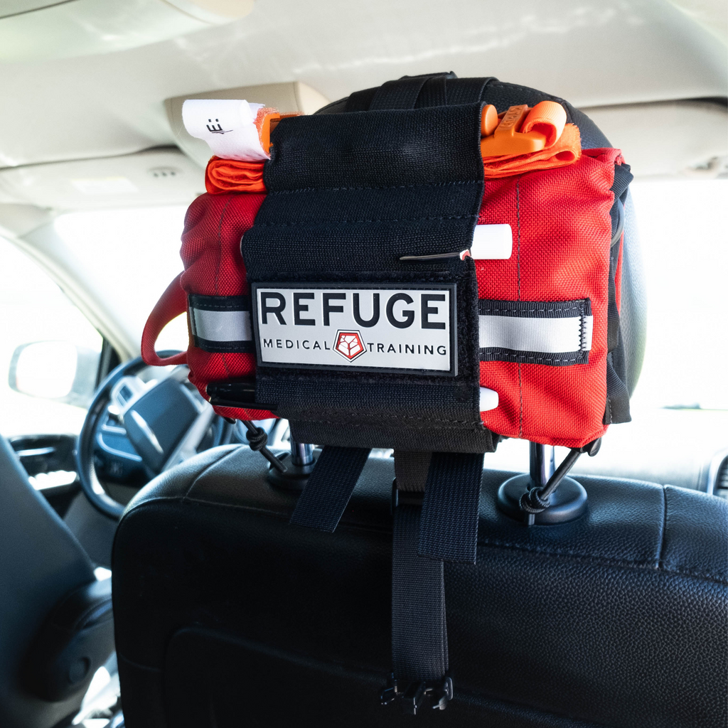 Refuge MedicalTravel FAK First Aid Kit - Red, mounted on the headrest of a car