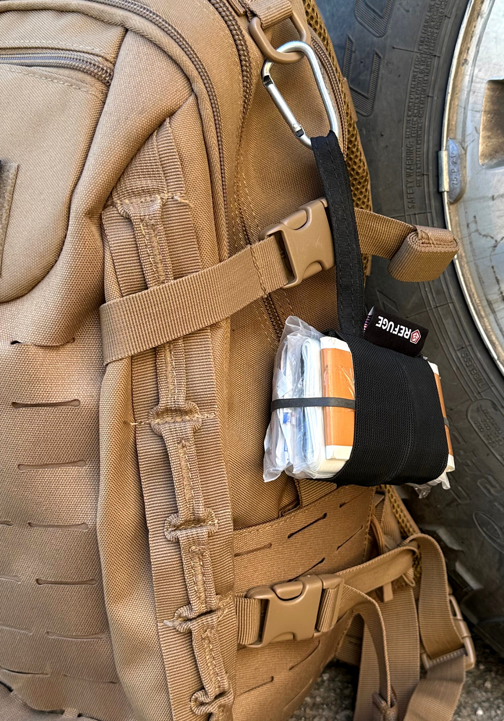 Black Boogie first aid kit hanging off a backpack from a carabiner 